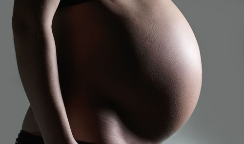 Midsection of woman standing against black background