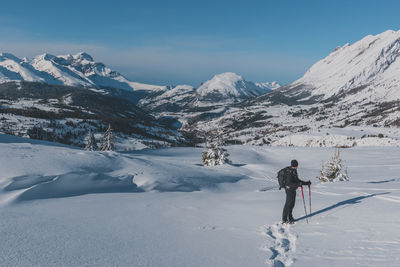 An unrecognizable male hiker wearing snowshoes walking in the french alps