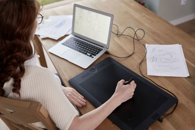 Midsection of woman using laptop on table