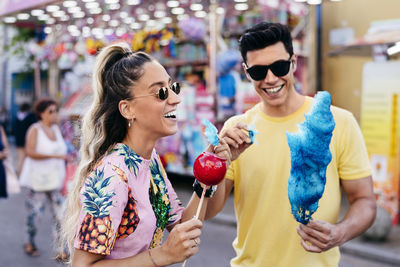 Satisfied man feeding girlfriend with cotton candy