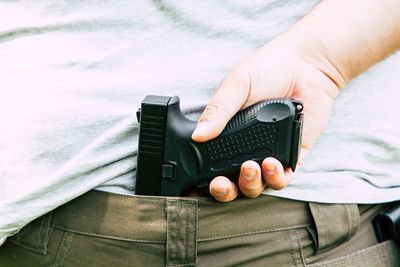 Midsection of man holding handgun