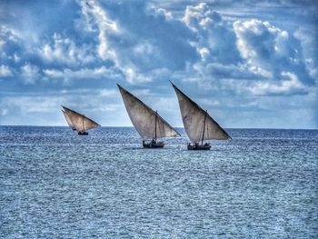Dhows of zanzibar sailing in ocean against a stormy sky