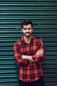 Portrait of young man standing against wall