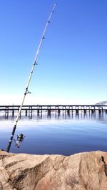 Scenic view of lake against clear blue sky with fishing pole