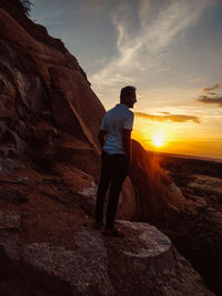 Man standing on rock at sunset