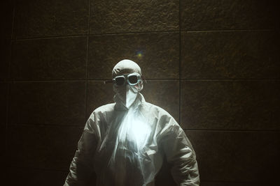 Young man in protective workwear standing against wall