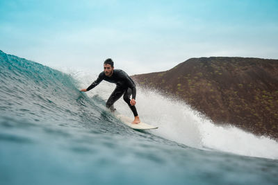 Man surfing in sea against sky