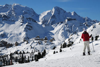 Rear view of man on snowcapped mountain against sky