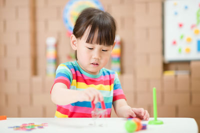 Full length of cute boy holding colorful table
