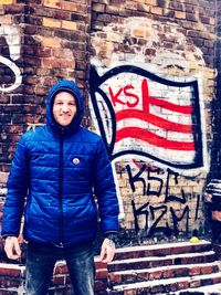 Portrait of man standing against graffiti wall