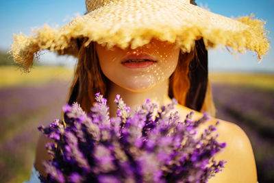 Portrait of young woman wearing hat holding lavender flowers 