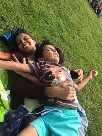 Smiling woman lying down with children on field