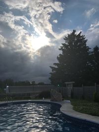 Swimming pool by lake against sky during sunset