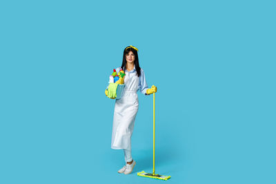 Full length of woman standing against blue background