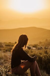 Woman looking at camera against sky during sunset