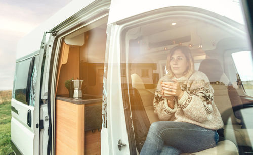 Woman with a cup sitting in the front seat of a camper van