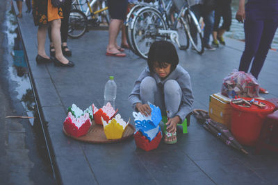 High angle view of girl selling colorful paper containers on street in city