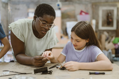 Female teacher helping student working on robotics project in technology class at school