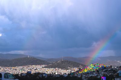 Rainbow over city against sky