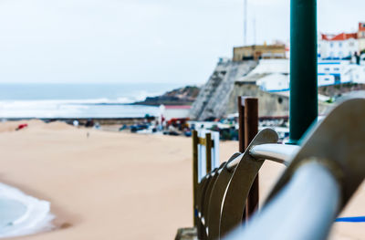 Close-up of deck chairs on beach against sky