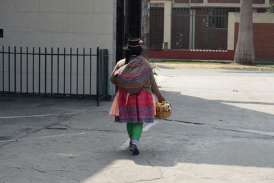 Rear view of woman walking on sidewalk