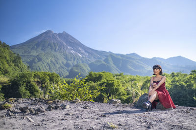 Woman sitting on landscape against mountains