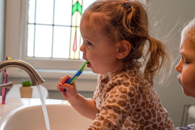 Cute girl brushing teeth at home