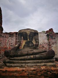Statue in front of temple against cloudy sky