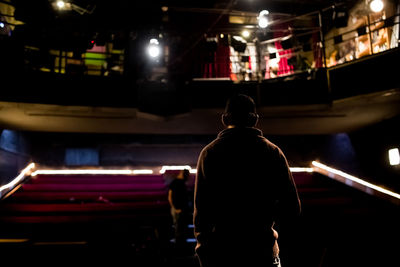 Rear view of man standing in dark auditorium