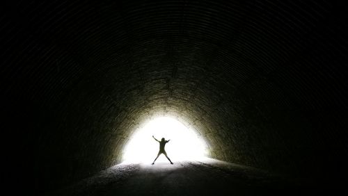 Silhouette person walking in tunnel