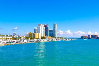 City at waterfront against blue sky