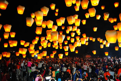 Large crowd looking at illuminated lanterns against sky at night