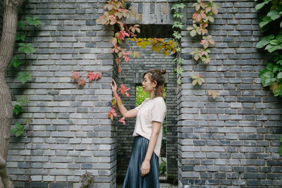 Full length of beautiful woman standing against brick wall