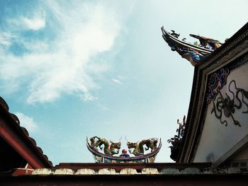 Low angle view of sculpture and building against sky