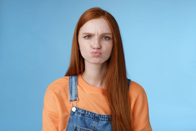 Young woman puckering against blue background