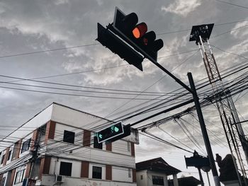 Low angle view of road signal against cloudy sky