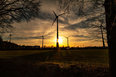 Silhouette of windmill on field against sky at sunset