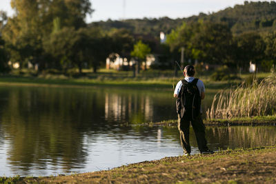 Rear view of man standing at lake