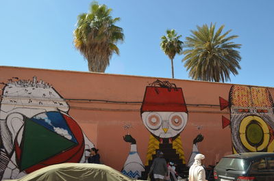 Low angle view of people on palm tree against sky