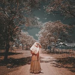 Woman standing by tree against plants