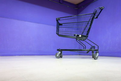 Low angle view of shopping cart against blue wall