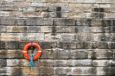 Life belt hanging against brick wall