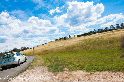 Panoramic view of road amidst field against sky