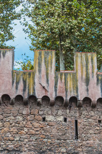 Low angle view of weathered wall against trees