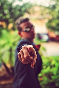 Close-up of woman hand holding flower against blurred background