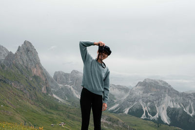 Woman overlooking seceda in dolomite mountains taking photos