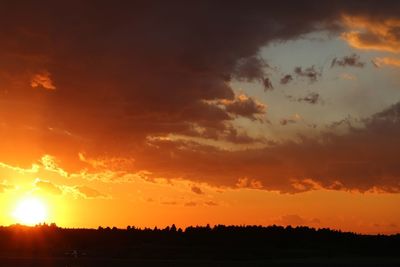 Scenic view of dramatic sky over silhouette landscape during sunset