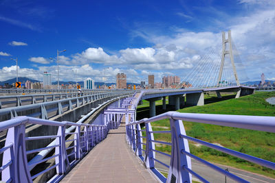 Footbridge against sky in city