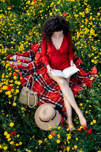 Midsection of woman sitting by flowering plants