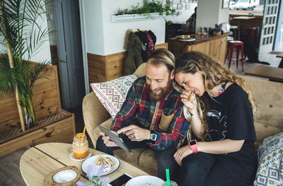 Couple having breakfast in cafe, looking at tablet pc